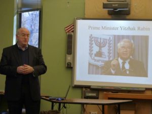 Ambassador Kurtzer stands in front of a slide showing Yitzhak Rabin.