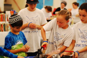 A sixth grader operates a button-making machine at the Shuk for Shalom.