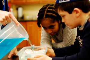 Fourth Grade students conducting a science experiment with colored water and clay.