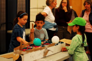 Students play cardboard arcade games together.