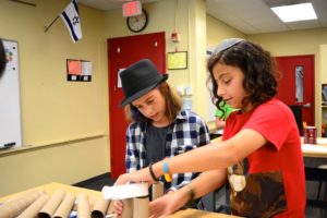 Students construct a prototype sukkah using cardboard tubes during the Sukkah Design Challenge.