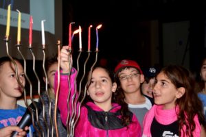 Students light the school chanukiah in front of their peers.