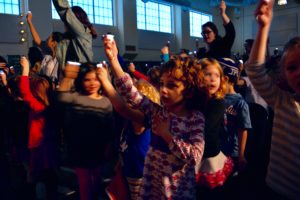 Students wave flashlights in the darkened auditorium.