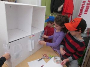 Students help decorate the doors on a set of cabinet shelves for the new library.