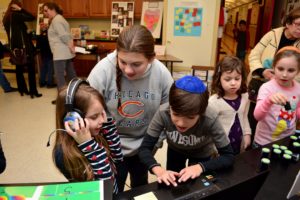 A sixth grader guides a younger student through a science activity.