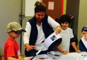 Parents and children work together in the school kitchen during Chesed Cooks.