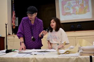 Third grader Batya S. reads from the Megillah at JPDS-NC's Purim celebration.