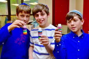 Three boys hold up their sand art.