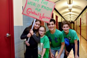 Students hold up a sign that reads, "Save the world from Global Warming."