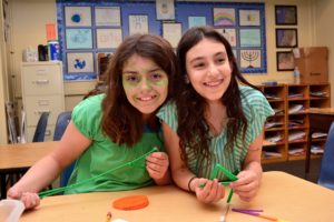 Students wearing green smile for the camera; one also has green face paint.