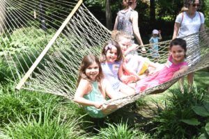 Three children share a hammock in the summer sun.