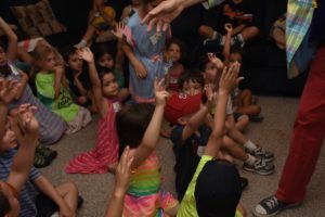 Children eagerly raise their hands to be volunteers for the magician at the Summer Brunch.