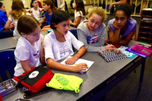 Sixth graders sit together at a classroom table.