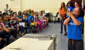 A fourth grade student blows the shofar during tefilah for his peers.