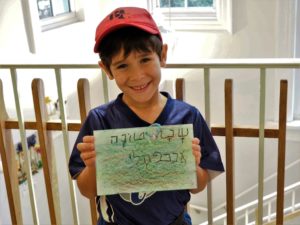 A student holds up a Rosh Hashanah card that he wrote in Hebrew.