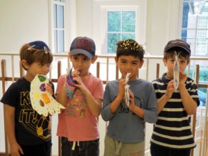 Four students pretend to blow into paper shofars that they have decorated.