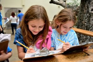 Two students compare notes at one of the zoo's indoor animal houses.