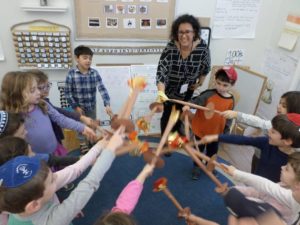 Kindergarten students wave paper torches with Hebrew teacher Gili Bitton as they sing the Hebrew Hanukkah song, "Banu Choshech Legaresh" (We Have Come to Send Away the Darkness."