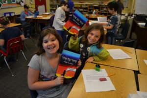 Fourth graders check out their new siddurim with their friends.