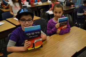 Third graders enjoy their new siddurim.