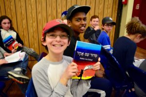 A sixth grader smiles upon receiving his siddur.