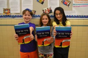 Students show off their brand new siddurim in the hallway.