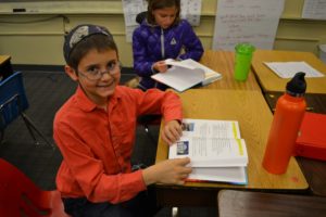 A fourth grader reads from his new siddur.