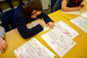 A student writes carefully, recording her observations about her character.