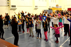 The Gottesman Auditorium is filled with children and adults waving their hands in time to the music.