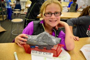 A student displays a prototype of her invention.