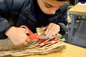 A student precisely trims materials to use in the sukkah design challenge.