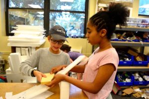 Two students construct a model of a building together.