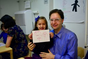 A student shows off her self-portrait with her father.