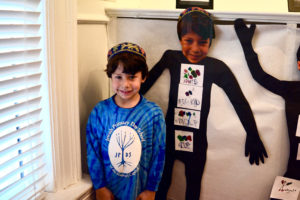 A student stands next to his self-portrait with adjectives.