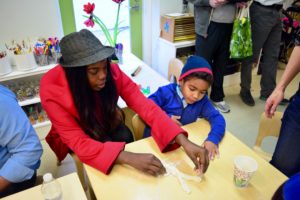 A Pre-Kindergarten student and his mother braid challah together.