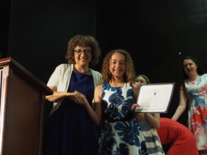 Head of School Naomi Reem congratulates a graduate and gives her a certificate of graduation.