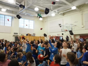 Students throw hats in the air during the moving-up ceremony.