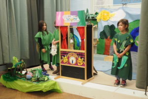 Students dressed in brilliant green costumes perform onstage.