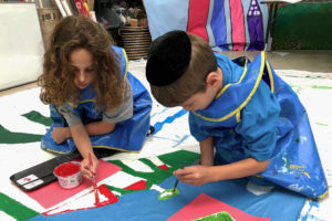 Two students paint a backdrop in preparation for their class play.