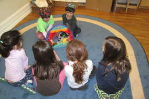 Two students perform a puppet show for four of their classmates.