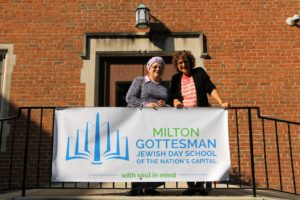 Founding Head of School Susan Koss and current Head of School Naomi Reem pose in front of the Milton banner.