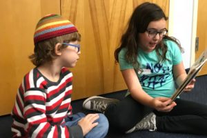 A fourth grade student reads to her Kindergarten reading buddy.