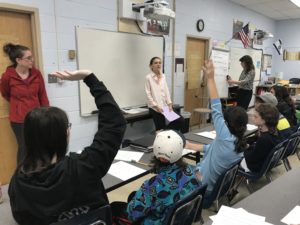 Sixth graders raise their hands during a discussion with Nahanni Rous.