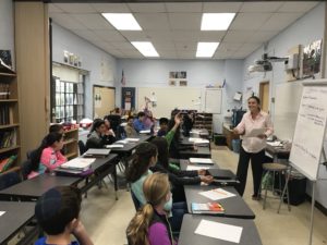 Podcast producer Nahanni Rous speaks in front of a classroom of sixth graders.