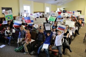 Students hold up signs of their country's flags and delegates.