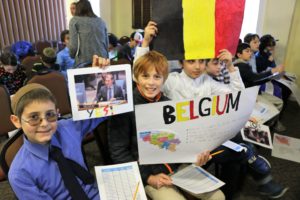 Students representing Belgium at the recreation of the U.N. Partition Vote hold up signs, flags, and photographs.