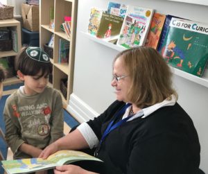 First grade Hebrew and Judaic Studies teacher Silvia Edenburg reads a story with a student.