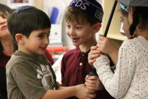 First grade boys share an umbrella as the students sing together in Hebrew.