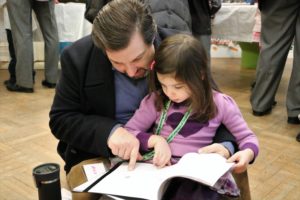 A Kindergarten student reads a museum booklet with her father.