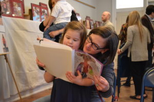 A student reads her homemade book with her mother at the Pre-K Bayit Patuach (Open House).